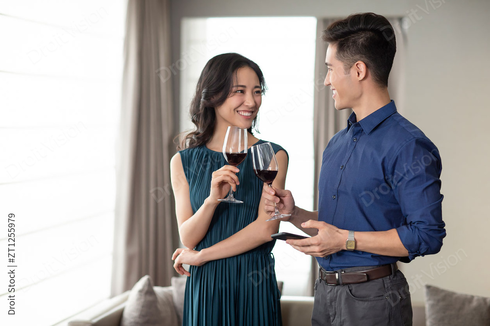 快乐的年轻夫妇在客厅喝红酒图片