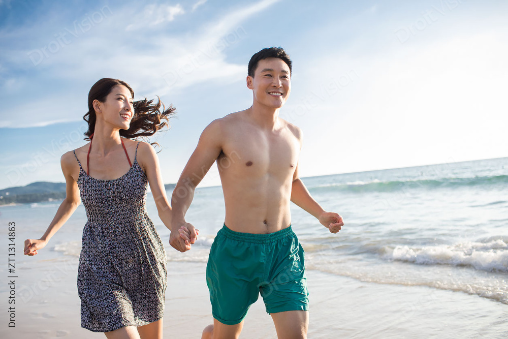 快乐的年轻情侣在沙滩奔跑图片