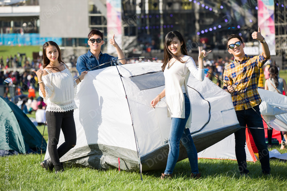 年轻人在草地上搭建帐篷图片