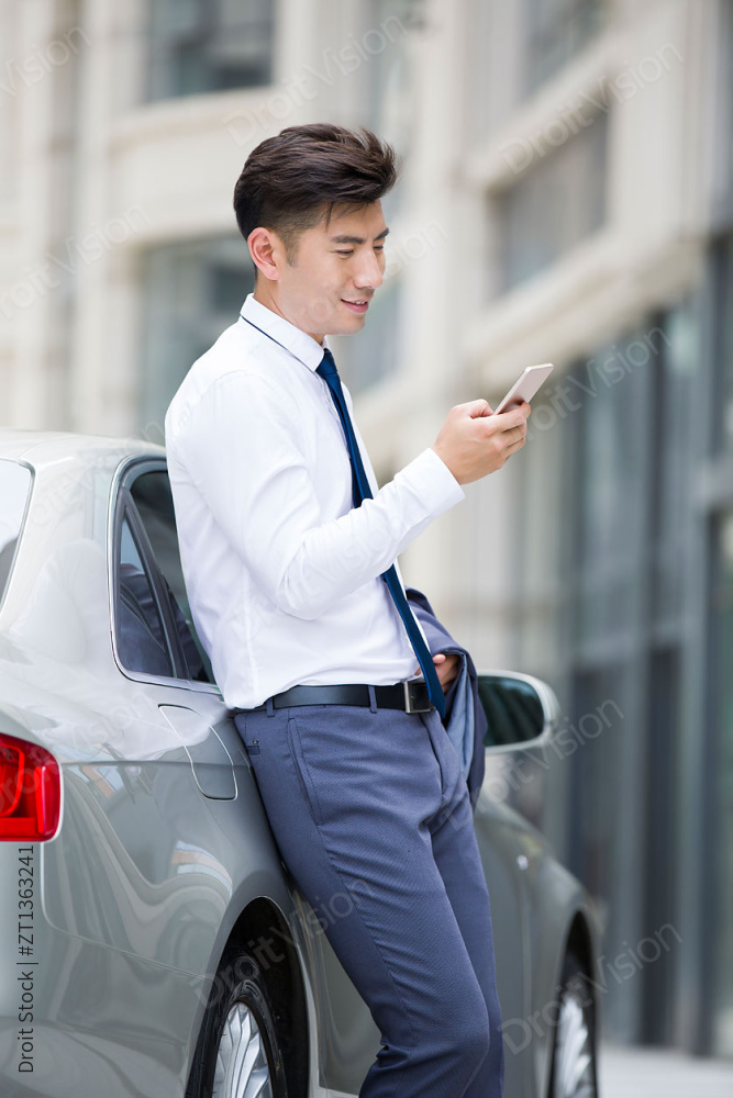 商务男士倚靠汽车看手机图片