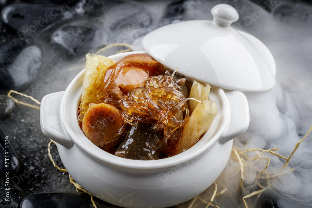 养生佛跳墙摆放在干冰缭绕的黑色鹅卵石山图片