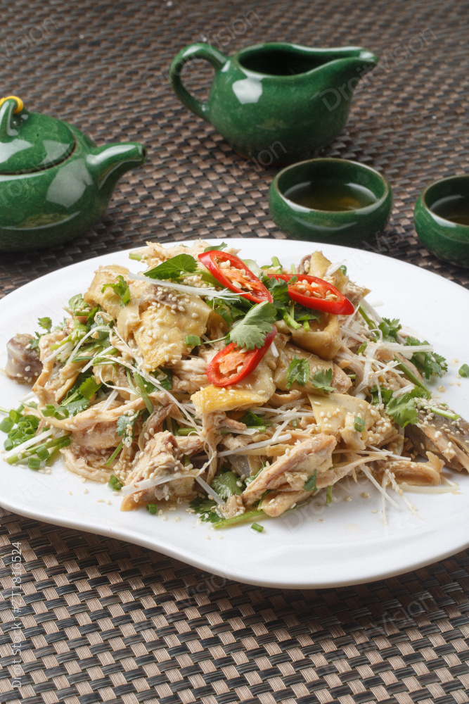 扇形白瓷盘装的麻辣手撕鸡摆放在餐垫上图片