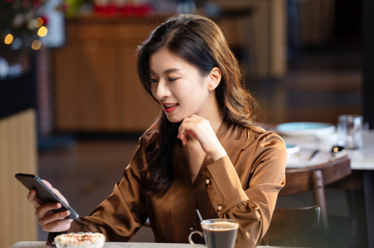 咖啡馆内边喝咖啡边使用手机的青年女人