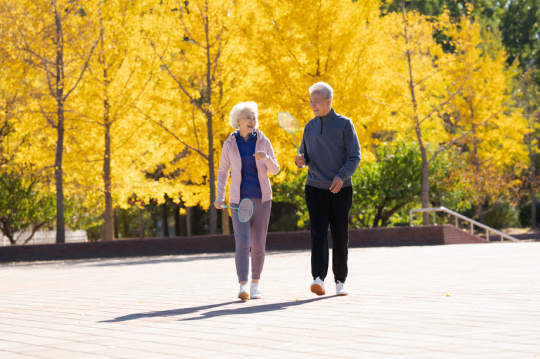 户外的老年夫妇拿着羽毛球拍