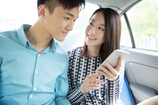 青年情侣在车内看手机