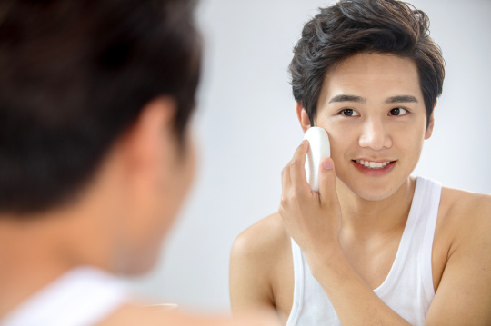 对着镜子用面扑擦脸的年轻男人