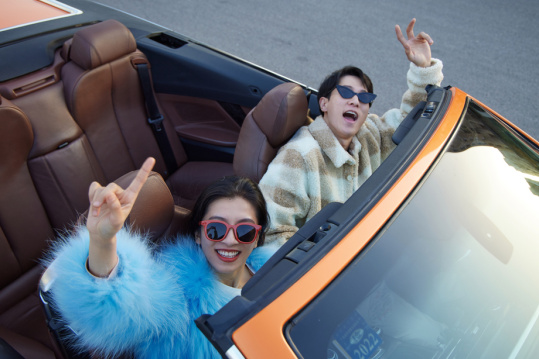 快乐的青年情侣驾驶跑车出行