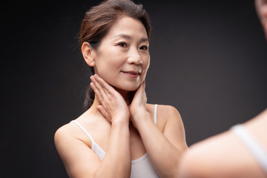 镜子里做颈部护理的中年女性