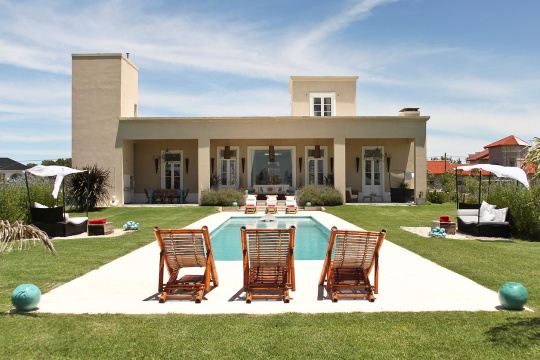 Deck chairs by swimming pool in front of house