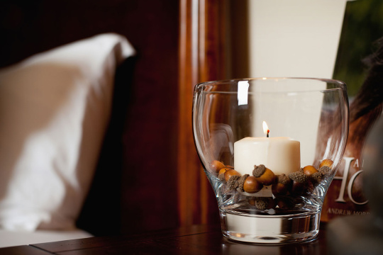 Detail of lit candle in glass holder on table at home; Scottsdale; USA