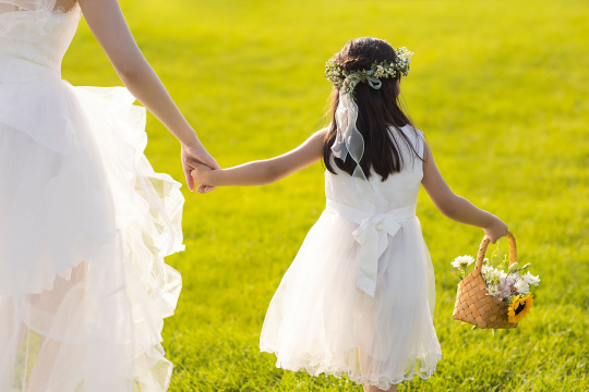 可爱的婚礼花童和新娘在草地上玩