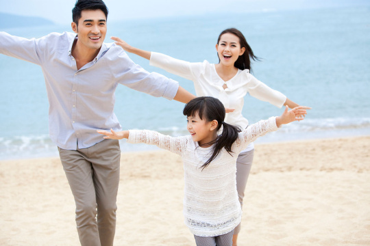 快乐的一家三口在沙滩上玩耍