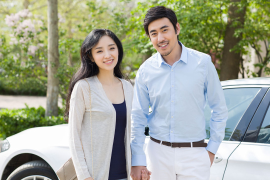 快乐的年轻夫妇站在汽车旁