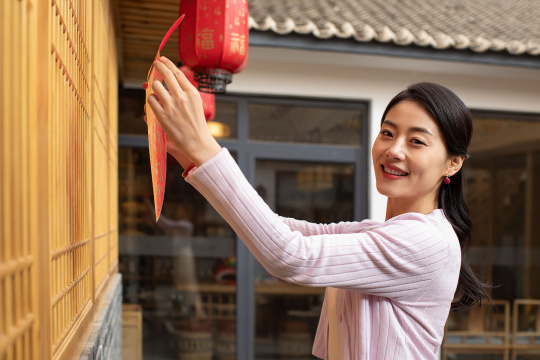 快乐的年轻女子贴窗花迎新年