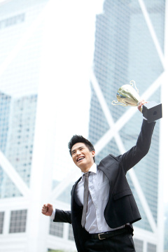 兴奋商务男士举着奖杯庆祝