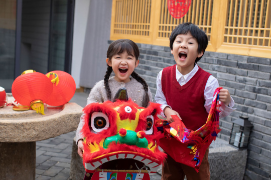 快乐的兄妹俩在院子里舞狮子