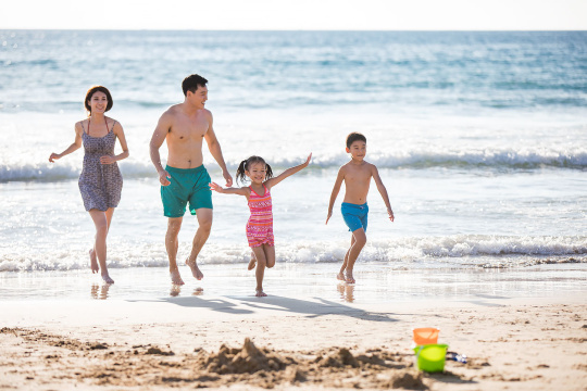 快乐的年轻家庭在沙滩奔跑