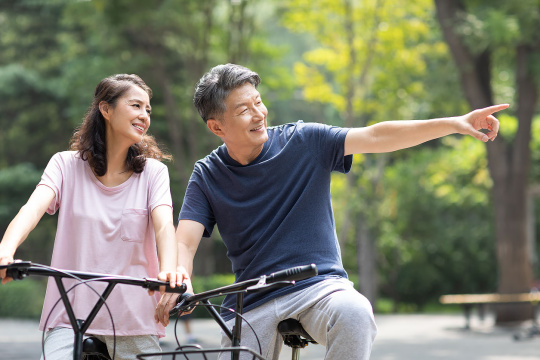 快乐的成熟夫妇在公园骑自行车