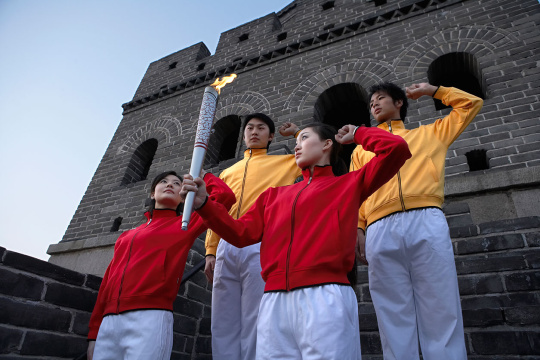 四位身穿运动服的年轻人在奥运火炬前宣誓