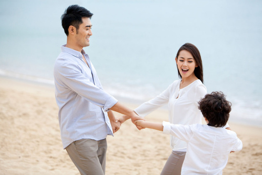 快乐的一家三口在沙滩上玩耍