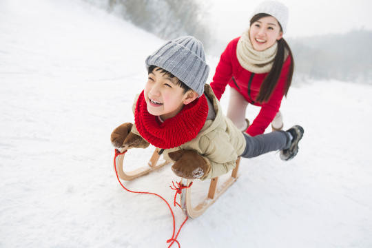母子俩在雪地上玩雪橇
