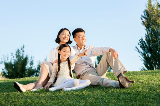 快乐的一家三口坐草地上