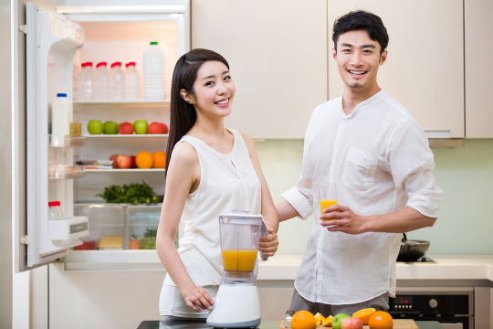 年轻女士为丈夫榨橙汁