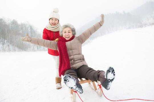 奶奶和孙女在雪地上玩雪橇