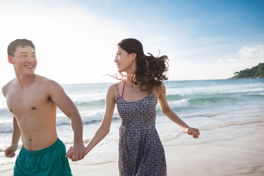 快乐的年轻情侣在沙滩奔跑