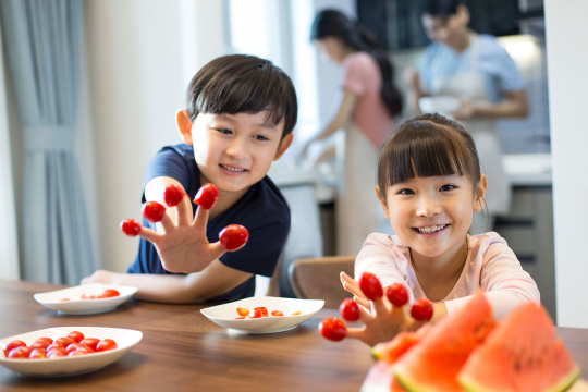 快乐的兄妹俩拿着小番茄玩