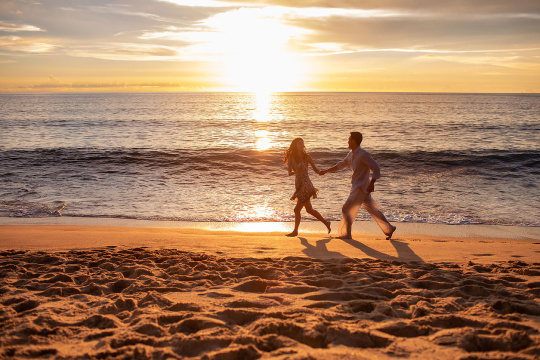 快乐的年轻夫妇在沙滩奔跑