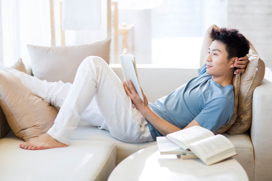 年轻男子在沙发上看书