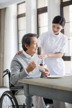 护工照顾坐着轮椅的老年男子