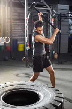 年轻男子在健身房锤击大轮胎