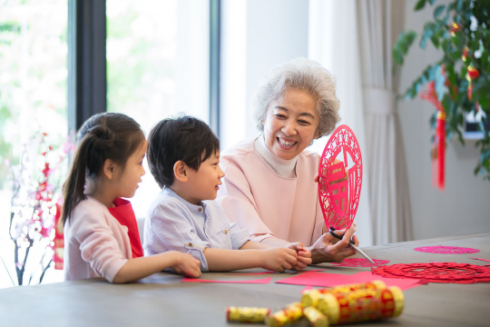 快乐的奶奶教孙子们剪新年窗花