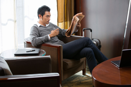 年轻商务男士在宾馆看报纸