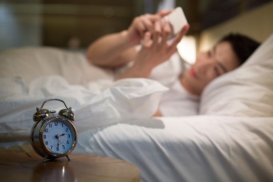 年轻男子半夜在床上玩手机