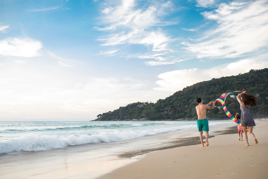 快乐的年轻家庭在沙滩放风筝