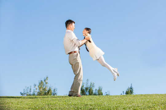开心的爸爸在公园抱起小女孩
