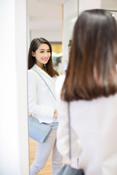 年轻女子在服装店照镜子