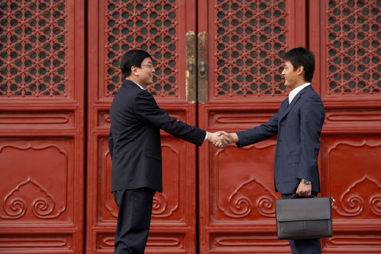 两位商务男士在太庙前握手