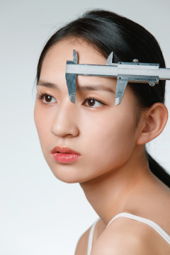 整形医生用卡尺测量青年女人面部