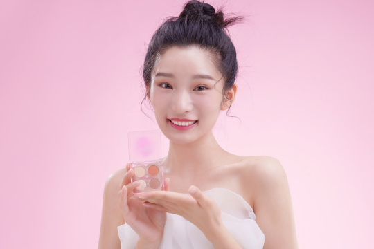 漂亮的青年女人拿着眼影盘