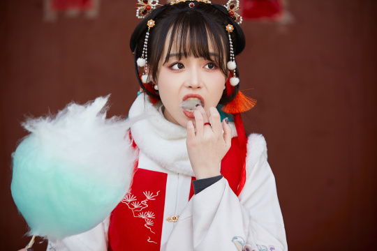 身穿喜庆汉服吃棉花糖的少女