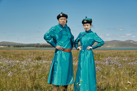草原上蒙古包前穿蒙古族传统服饰的年轻夫妻