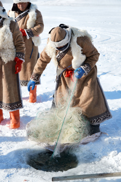 寒冷的冬季在冰冻的湖面上凿冰捕鱼的人们