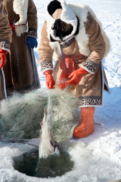 寒冷的冬季在冰冻的湖面上凿冰捕鱼的人们