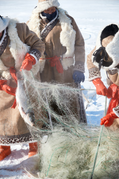 寒冷的冬季在冰冻的湖面上凿冰捕鱼的人们