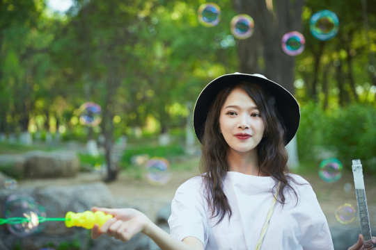户外公园里玩吹泡泡的可爱亚洲少女