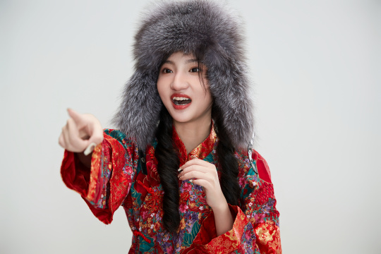 白色背景下穿中国传统服饰头戴绒帽的少女